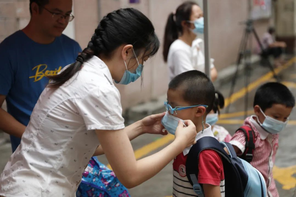 老师帮孩子戴好口罩